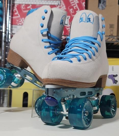 White roller skates with blue accents on a white surface, with a boxes in the background.