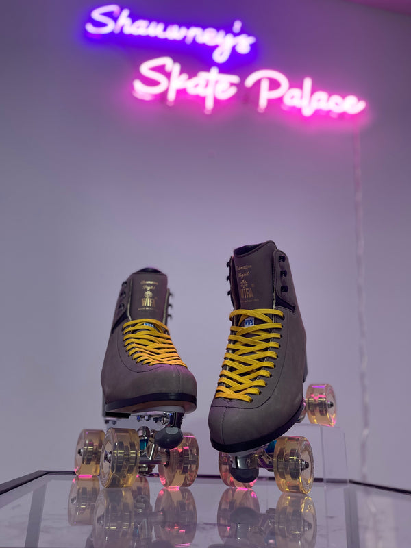 Pair of roller skates with yellow laces in front of a neon sign reading 'Shawmey's Skate Palace'.