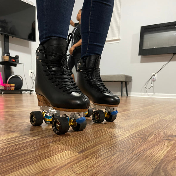 Person wearing black roller skates on a wooden floor